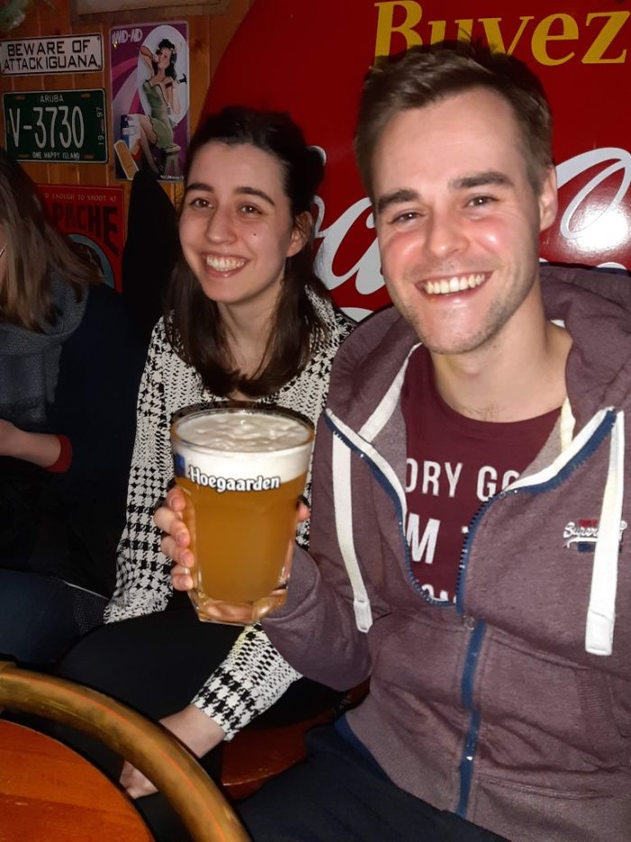 Twee jongeren, vrouw en man met groot glas bier in café